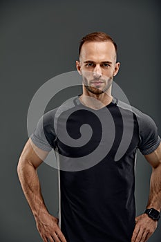 Studio male portrait of handsome powerful athletic man model with healthy muscular body in fashionable black tank top