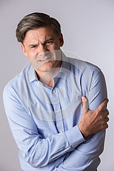 Studio Of Mature Man Clutching Arm As Warning Of Heart Attack