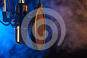 Studio microphone on mic stand against .Color disco background. Vocals and radio, podcasts, colored smoke