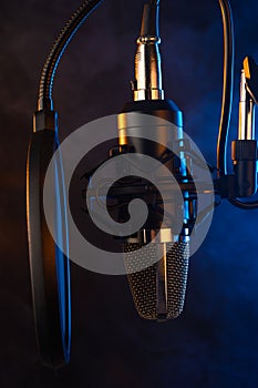 Studio microphone on mic stand against .Color disco background. Vocals and radios, podcasts, colored smoke. Vertical photo