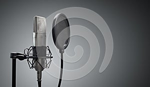 Studio microphone and pop shield on mic stand against gray background