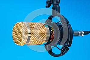 Studio microphone for recording podcasts, songs, and radio programs on a blue background with a place for inscription photo