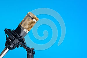 Studio microphone for recording podcasts, songs, and radio programs on a blue background with a place for inscription photo