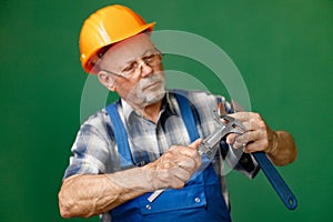 Studio photo of a man worker holding tools isolated on green background