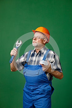 Studio photo of a man worker holding tools isolated on green background