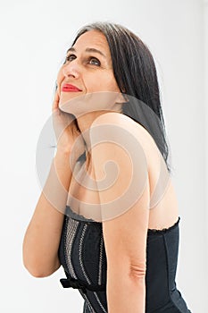 Studio photo of middle aged woman starting getting grey-haired wearing black and white clothes on white background