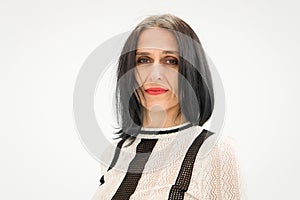 Studio photo of middle aged woman starting getting grey-haired wearing black and white clothes on white background