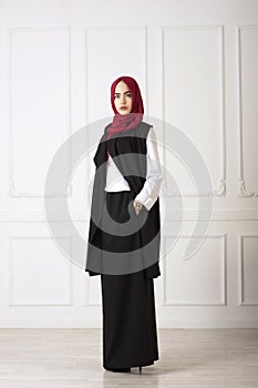 Studio photo of an oriental woman in a modern Muslim clothing, a scarf and a gold watch hand well