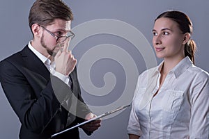 Studio photo Portrait of a pair of young people of twenty-five years old. in business clothes. The boss lowers his glasses,