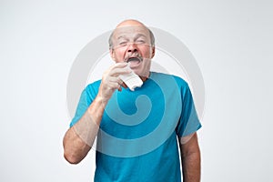 Studio picture of senior man with handkerchief. Sick guy isolated has runny nose.
