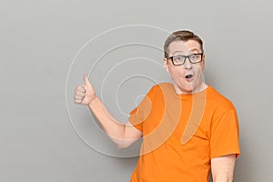 Portrait of amazed impressed man raising thumb up in approval gesture photo