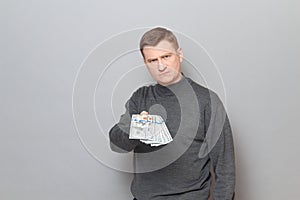 Portrait of angry annoyed man stretching out his hand with money ahead