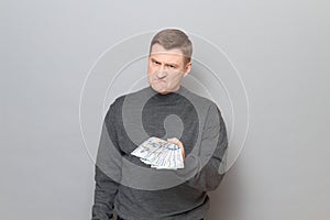 Portrait of angry annoyed man stretching out his hand with money ahead