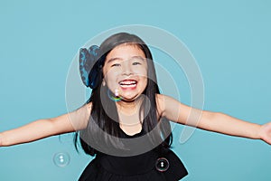 Studio portrait of asian girl with soap bubbles in front of blue background