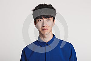 A studio portrait of an Asian man who looks displeased and disappointed
