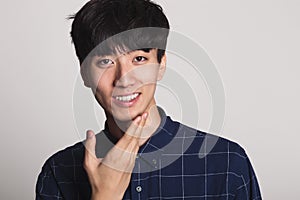 A studio portrait of an Asian young man smiling with a bright smile