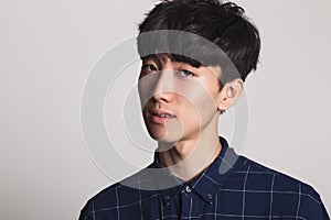 A studio portrait of an Asian young man smiling with a bright smile