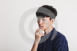 A studio portrait of an Asian young man who is troubled and deep in thought