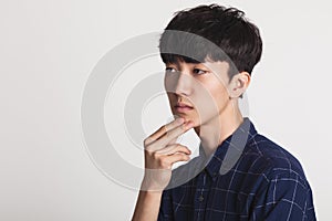 A studio portrait of an Asian young man who is troubled and deep in thought