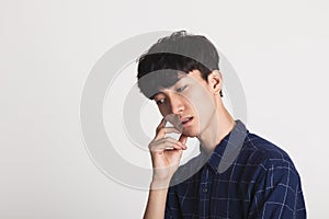 A studio portrait of an Asian young man who is troubled and deep in thought