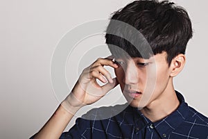 A studio portrait of an Asian young man who is troubled and deep in thought