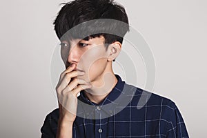 A studio portrait of an Asian young man who is troubled and deep in thought