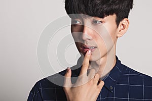 A studio portrait of an Asian young man who is troubled and deep in thought