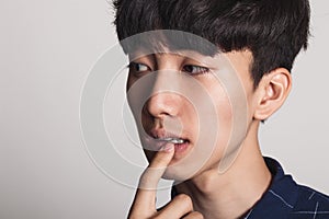 A studio portrait of an Asian young man who is troubled and deep in thought