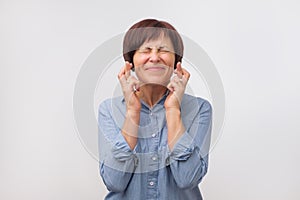 Studio portrait of attractive mature woman having excited, superstitious and naive look, keeping fingers crossed