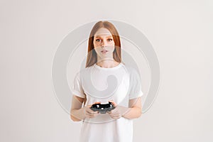 Studio portrait of attractive young woman playing video game with controller looking at camera on white