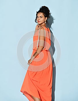 Studio portrait of beautiful attractive charming young brunette woman wearing greek inspired dress coral col