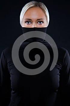 Studio portrait of beautiful elegant woman hiding face in black turtleneck