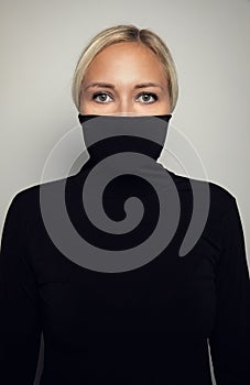 Studio portrait of beautiful elegant woman protect her face in black turtleneck