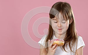 Studio portrait of a beautiful little girl holding a donut and smelling tasty flavour photo