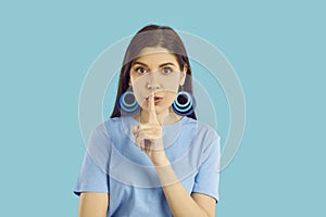 Studio portrait of beautiful woman doing shush gesture and asking you to keep her secret