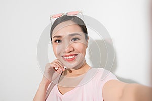 Studio portrait of beautiful woman smiling with white teeth and making selfie, photographing herself over white background