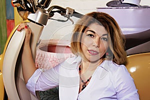 Studio portrait of a beautiful woman in white shirt posing with motorbike