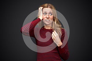 Studio portrait of a beautiful young blonde woman with disturbing upset shocked expression on her face.