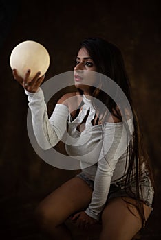 Studio portrait of a beautiful and young Indian Bengali female model in white cold shoulder top and jeans hot pant.