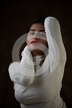 Studio portrait of a beautiful and young Indian Bengali female model in white cold shoulder top and jeans hot pant.
