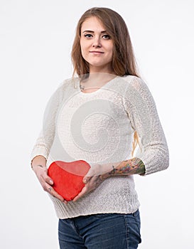 Studio portrait of beautiful young pregnant woman holding heart and posing on white background