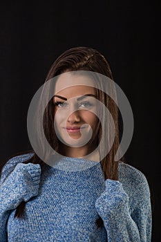 Studio portrait of beautiful young woman with long brown hair wearing blue sweater