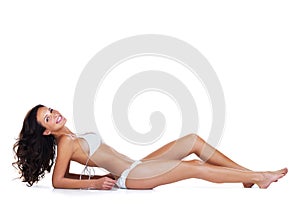 The perfect beach body. Studio portrait of a beautiful young woman reclining in a white bikini while being against a