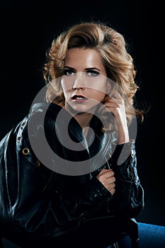 Studio portrait of blonde woman in leather biker jacket.