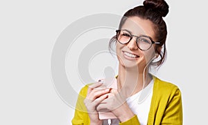 Studio portrait of brunette pretty smiling young woman using cellphone, to listening the music.