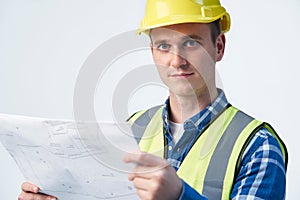 Studio Portrait Of Builder Architect Looking At Plans Against White Background