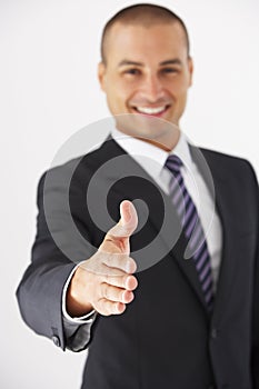 Studio Portrait Of Businessman Reaching Out To Shake Hands