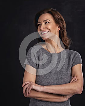 Studio portrait of a cheerful smiling brunette haired woman against isolated black background