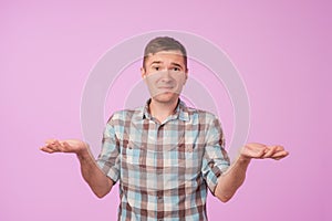 Studio portrait of confused handsome guy showing I have no idea gesture.