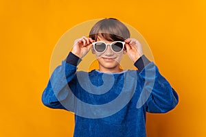 Studio portrait of a cool smiling teen boy putting on some sunglasses.
